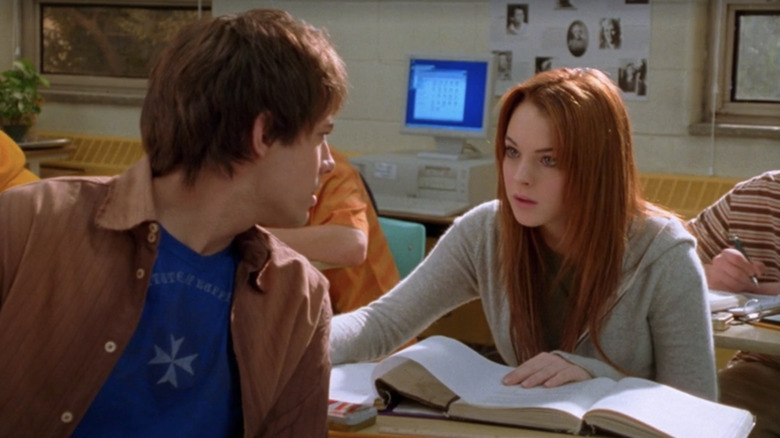 Cady Heron (Lindsay Lohan) dreamily smiles at Aaron Samuels (Jonathan Bennett) who is turned around to face her while sitting in their classroom desks in a scene from Mean Girls