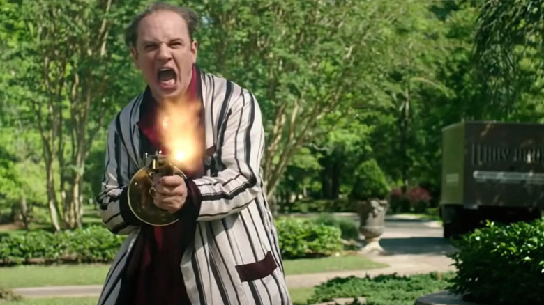 Tom Hardy firing a machine gun in a bath robe as Al Capone in Capone