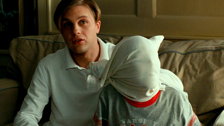 Paul sitting next to a boy with a pillowcase over his head in Funny Games