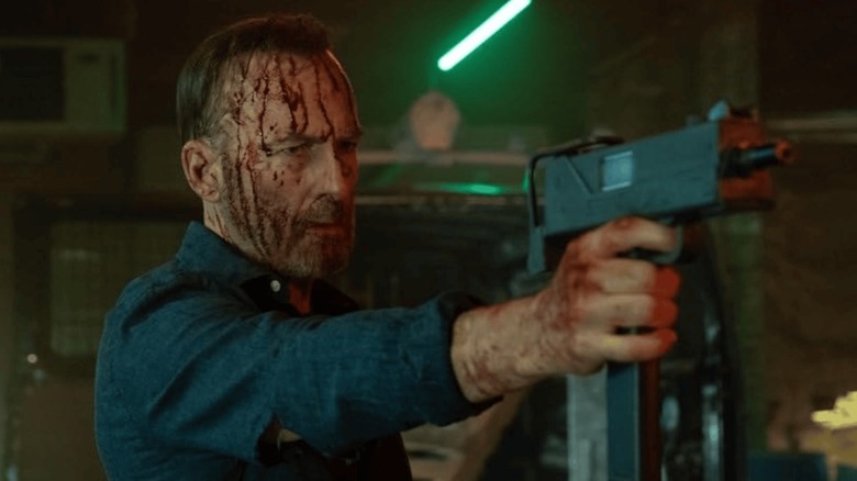 Bod Odenkirk as Hutch holding a machine gun bloodied up in Nobody 2