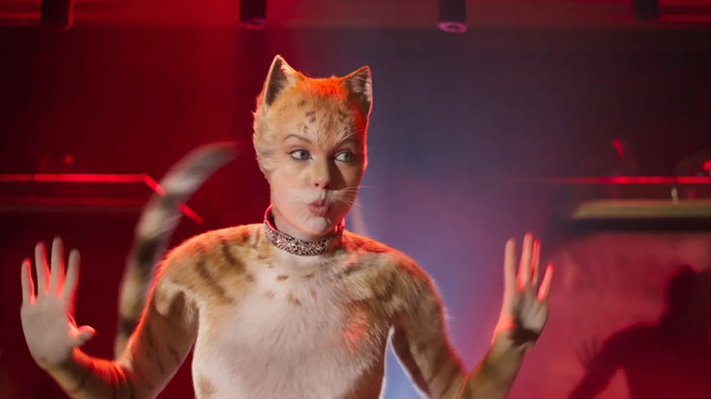 Bombalurina with her hands raised singing in Cats