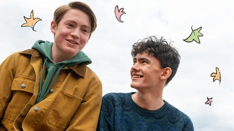 Kit Connor as Nick and Joe Locke as Charlie both smiling with animated leaves around them in Heartstopper