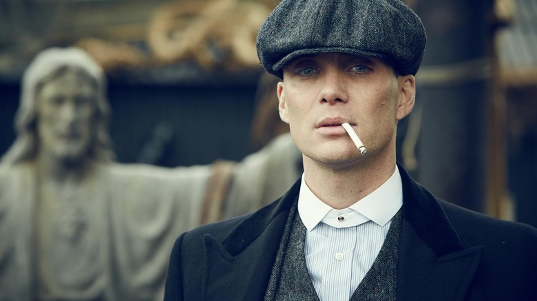 Tommy Shelby (Cillian Murphy) smoking a cigarette in front of a statue of Jesus in Peaky Blinders