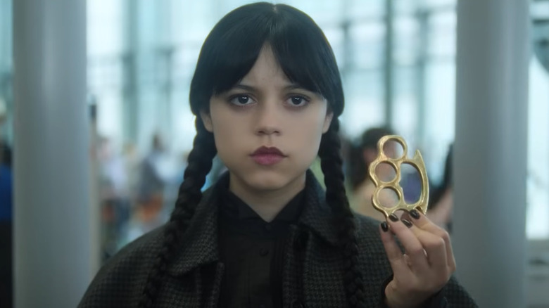 Jenna Ortega as Wednesday holding a pair of brass knuckles in Wednesday