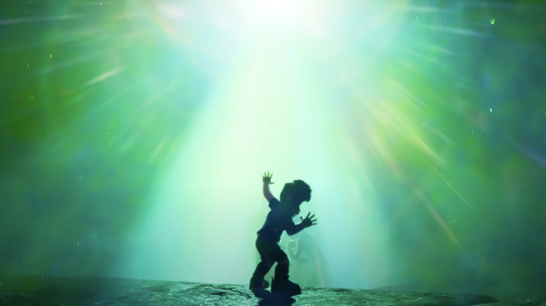Elio stands in front of a glowing beam of green light