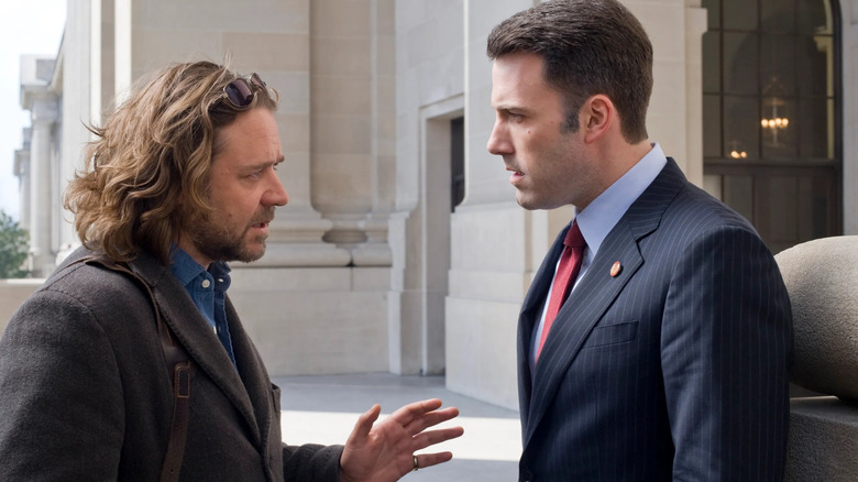 Cal McAffrey (Russell Crowe) and Stephen Collins (Ben Affleck) wear business suits and have an intense conversation with serious expressions outside a government building in a scene from State of Play