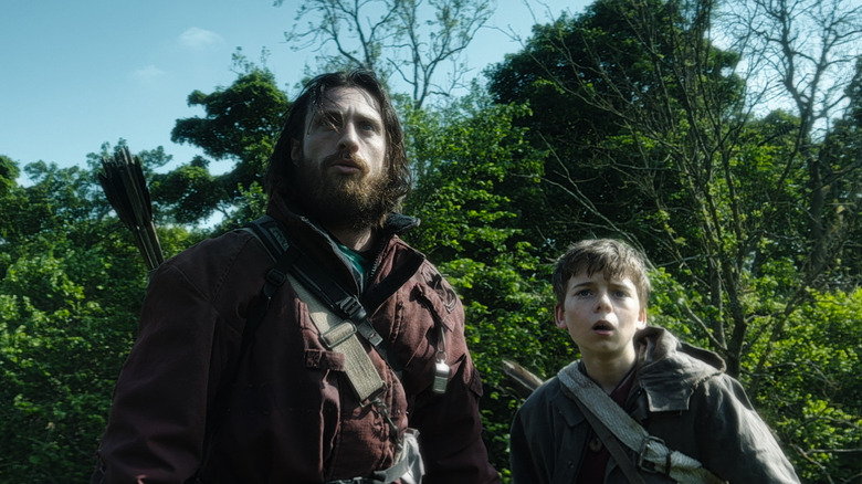 Jamie and Spike stand in front of some trees in 28 Years Later