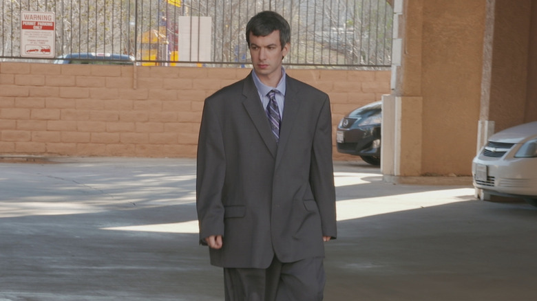 Nathan in an oversized David Lynch-style suit in a parking lot on Nathan For You