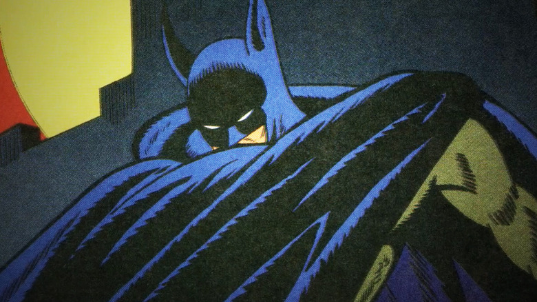 Batman pulls his cape across his face in a comic book panel shown in Batman & Bill