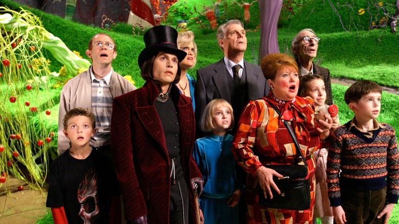 Willy Wonka and several kids and parents, standing in his candy factory in Charlie and the Chocolate Factory