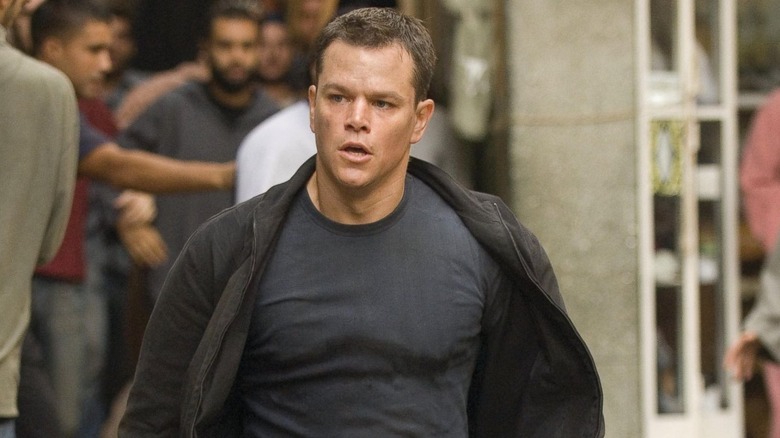 Jason Bourne runs down the crowded street in Morocco searching for answers in a blue shirt in 