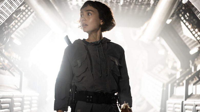 Wendy stands in a brightly light hallway in Alien: Earth