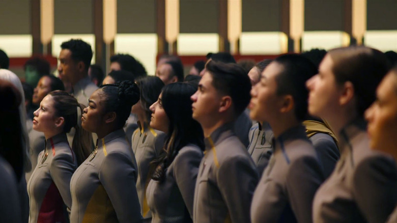 The cadets in Starfleet Academy stand at attention in their matching grey uniforms in 