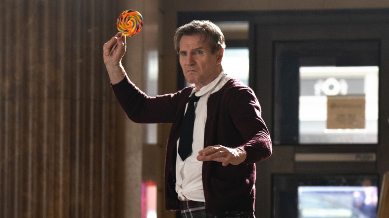 Liam Neeson as Frank Drebin Jr. using a sucker as a weapon in The Naked Gun (2025)