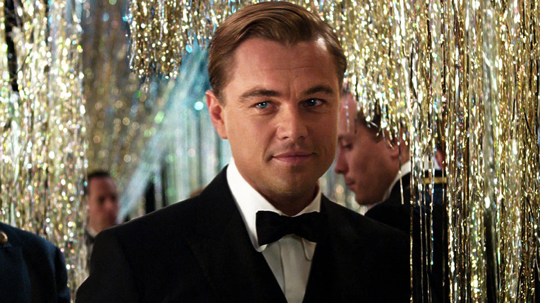 Jay Gatsby (Leonardo DiCaprio) donning a black suit and tie at one of his parties in 
