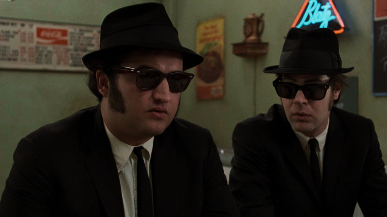 John Belushi and Dan Aykroyd in black suits, shades and trilbies as the Blues Brothers in the film of the same name.