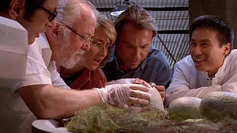 John Hammond, Ellie Sattler, and Alan Grant watching a raptor hatch from an egg in Jurassic Park
