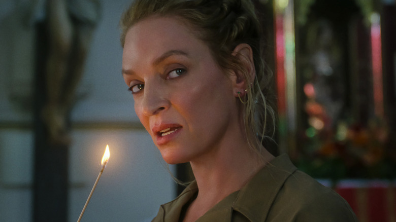 Uma Thurman as Discord holding a lit incense stick in The Old Guard 2