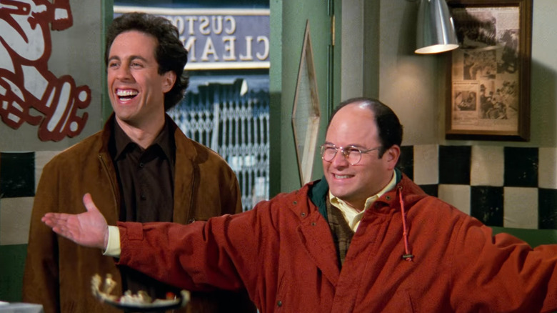 Jerry Seinfeld and George Costanza smiling in a pizza shop in Seinfeld