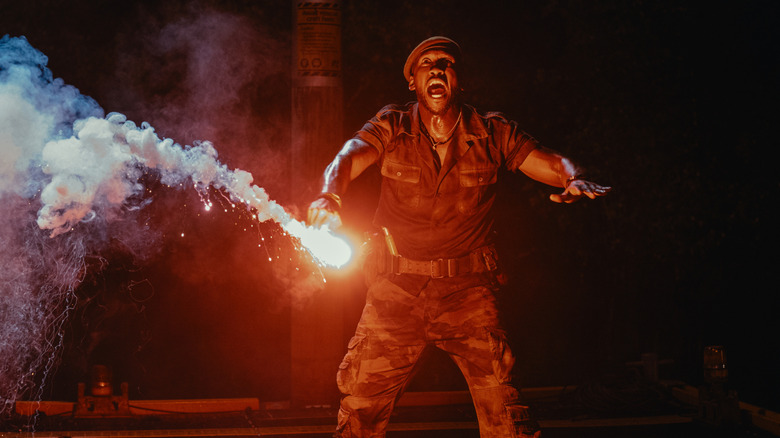 Mahershala Ali as Duncan Kincaid holding a flare to distract a dinosaur in Jurassic World Rebirth