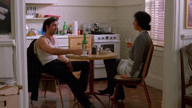 Nicolas Cage as Ronny Cammareri and Cher as Loretta Castorini sitting opposite each other at a kitchen table in Moonstruck