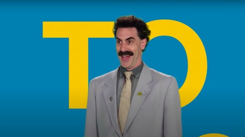 Sacha Baron Cohen flashes a great big goofy smile as Borat in Borat Subsequent Moviefilm