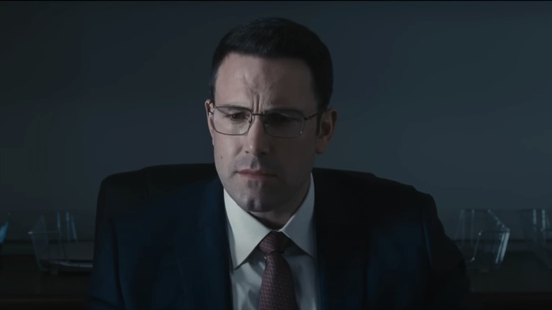 Ben Affleck's Christian Wolff  is seen sitting against a plain grey background in The Accountant