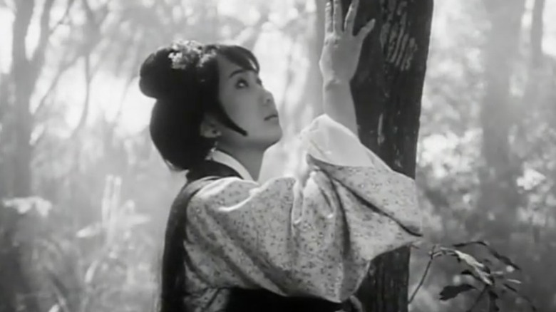 Lisa Lu as Madame Tung touching a tree with her right hand and looking up in The Arch