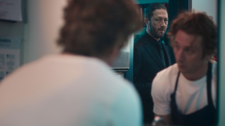 Richie looks at Carmy, who is looking at Richie reflected in a mirror in The Bear season 4