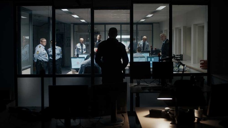 The Guilty (2018) shadowed shot of Asger Holm as other police officers look at him