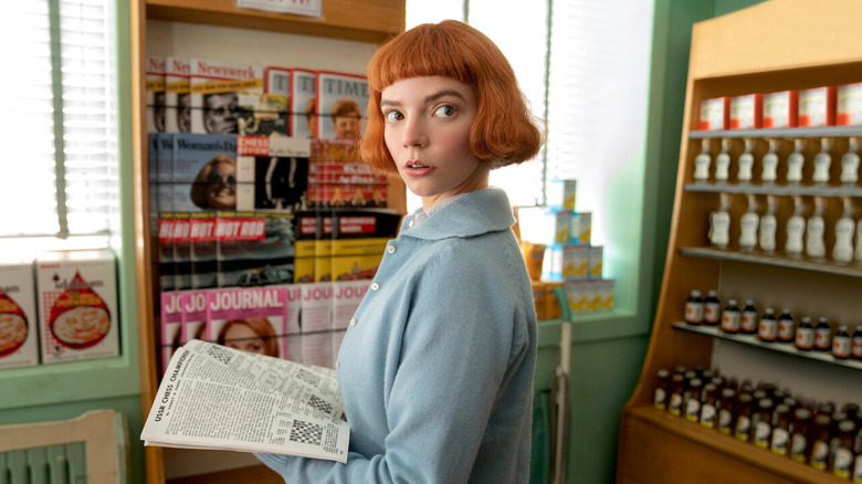 Beth Harmon (Anya Taylor-Joy) looks up from a newspaper in The Queen's Gambit
