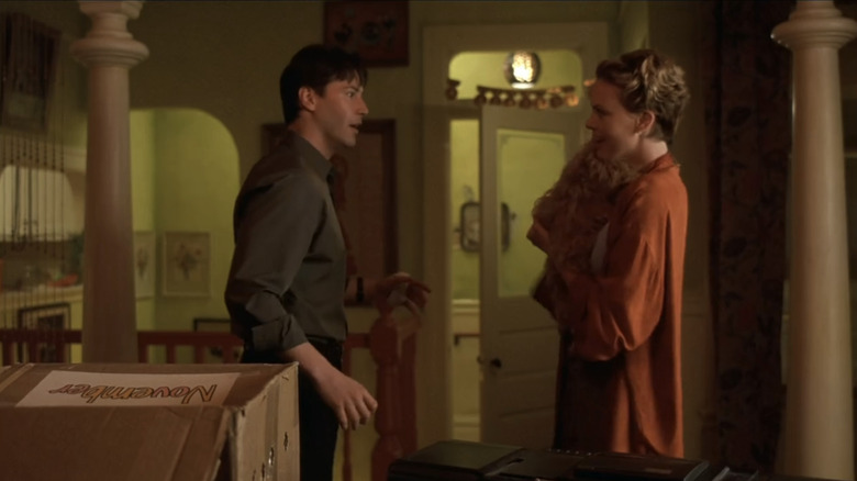 Keanu Reeves' Nelson Moss stands opposite Charlize Theron's Sara Deever in her apartment as she holds a dog in Sweet November