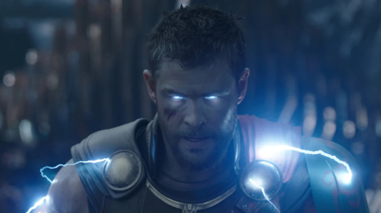 Chris Hemsworth as Thor with a shaved head and glowing electricity in his eyes and armor in Thor: Ragnarok