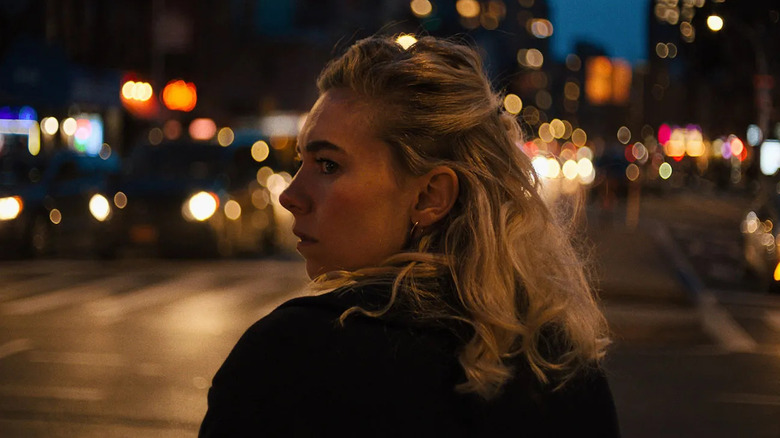Alina (Vanessa Kirby) stands on a city street at night, looking over her shoulder as car headlights and streetlights blur in the background in Italian Studies