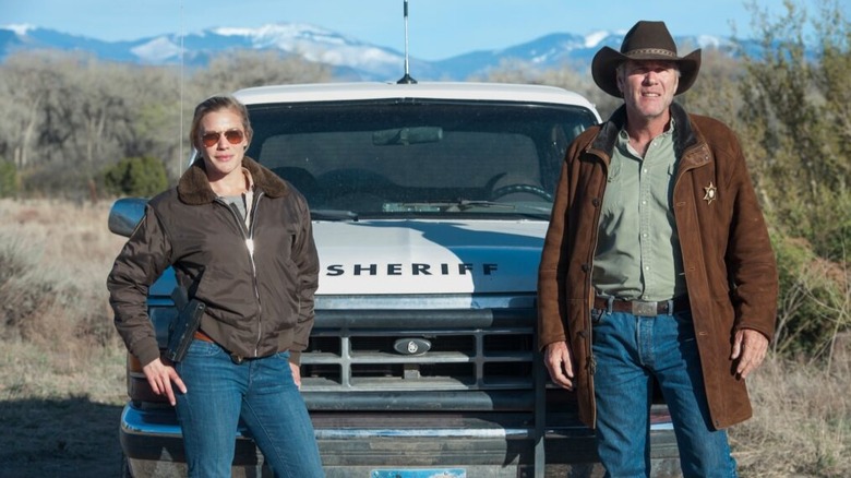 Victoria and Walt standing in front of a sheriff truck on Longmire
