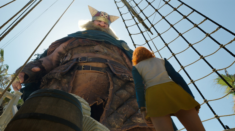 Grogy the giant stares at a tiny Nami in One Piece